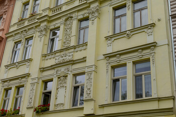 There is a bright yellow building featuring numerous windows along with vibrant flowers adorning the balconies, creating a charming atmosphere
