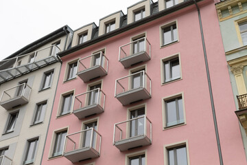 There is a pink building, characterized by having multiple balconies adorning its sides, creating a vibrant appearance against the sky