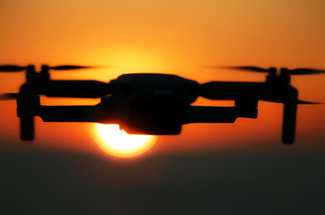Drone flying in the sky against the backdrop of a bright sunset. Radio-controlled quadcopter with a...