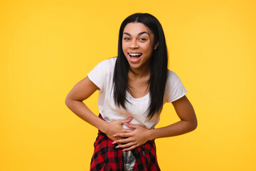 Obraz premium Emotional happy young african american woman black girl female afro student laughing out loud alone express positive emotion wearing casual clothes isolated over yellow background.