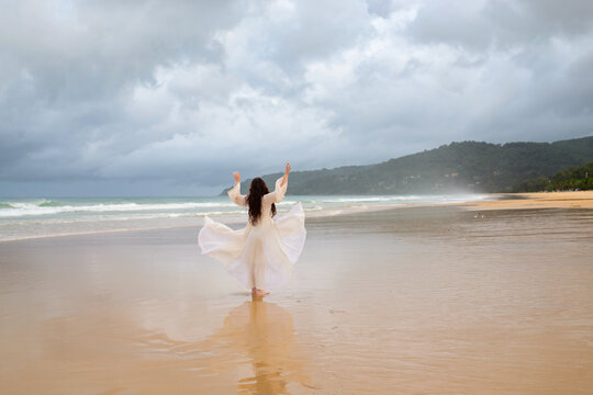 Back view young happiness asian traveller woman in white dress standing on beautiful sandy beach. Cute girl enjoy her tropical sea on relax holiday vacation during summer time