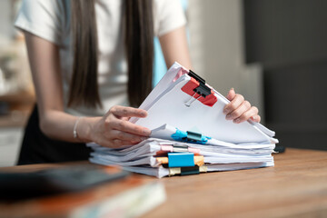 Businesswoman Reviewing Documents: A close-up of a businesswoman's hands meticulously reviewing a...