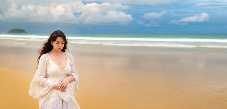 Portrait of young traveller woman in white dress and hat standing on beautiful sandy beach. Cute girl enjoy her tropical sea on relax holiday vacation during summer time and sunshine day