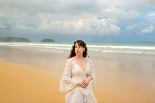 Portrait of young traveller woman in white dress and hat standing on beautiful sandy beach. Cute girl enjoy her tropical sea on relax holiday vacation during summer time and sunshine day