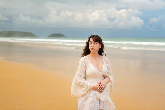 Portrait of young traveller woman in white dress and hat standing on beautiful sandy beach. Cute girl enjoy her tropical sea on relax holiday vacation during summer time and sunshine day