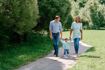 Multi-ethnic, African-American and European family walking down the road holding hands. Black baby,...