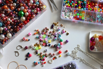 Colorful beads, letter beads, threads and other jewelry making supplies on white background. Making...
