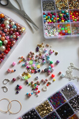 Colorful beads, letter beads, threads and other jewelry making supplies on white background. Making friendship bracelets concept. Selective focus.