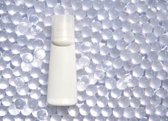 Minimalist white cosmetic bottle on transparent bead background for elegant spa and skincare branding.