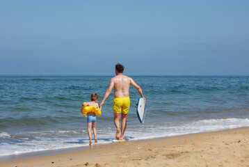 Dad and child enjoying summer with boogie board, floating ring