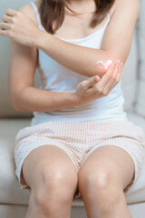 Arthritis and Muscle Pain Relief Cream concept. Woman having elbow ache at home, muscle pain due to lateral epicondylitis or tennis elbow. injury, Health and medical concept