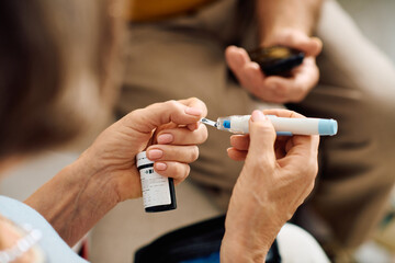 A supportive wife assists her husband as he prepares his diabetes medication at home.