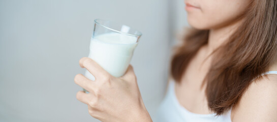 Milk drink and Daily Routine concept. Young woman Drinking milk with high calcium and nutrition at home, woman holding soy milk on glass with protein. Healthy, wellness and happy lifestyle