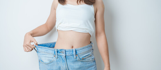 young slim female wearing big or oversize jeans, woman show healthy shape after weight loss....