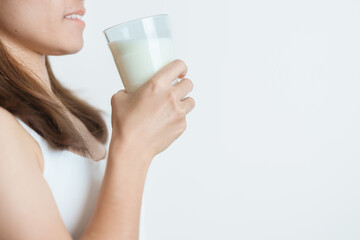 Milk drink and Daily Routine concept. Young woman Drinking milk with high calcium and nutrition at home, woman holding soy milk on glass with protein. Healthy, wellness and happy lifestyle