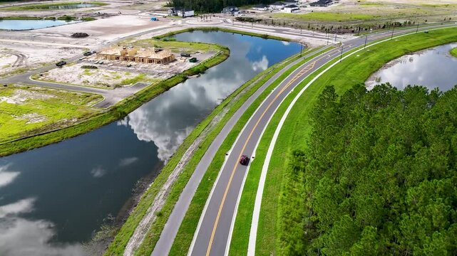 Cars driving on a winding road bordered by a pond and lush forest near Vilano Beach, Florida