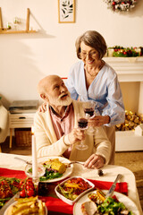 The couple raises their glasses in a toast, surrounded by a festive Christmas feast at home.