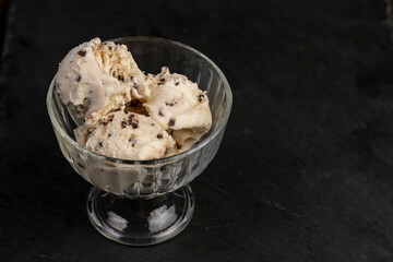 white creamy ice cream with pieces and crumbs of chocolate in a glass bowl