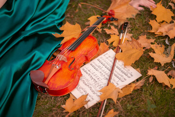 girl holding treble clef and violin on autumn leaves
