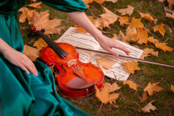 girl holding treble clef and violin on autumn leaves