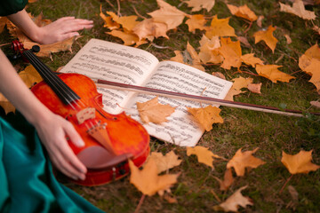 girl holding treble clef and violin on autumn leaves