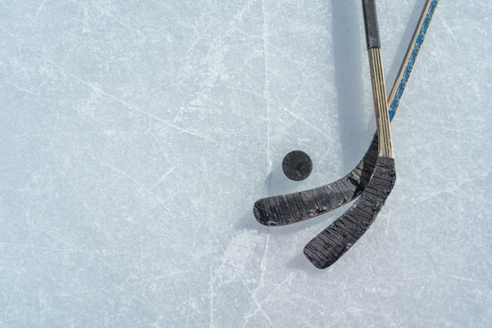 puck and ice hockey stick on the scratches surface abstract background ice arena