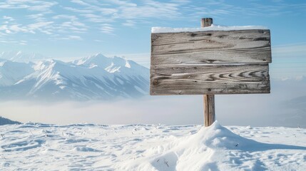 Naklejka premium A blank blue sign atop a snowy mountain with frozen trees in the blurry background, snow covered mountains and sky in the background