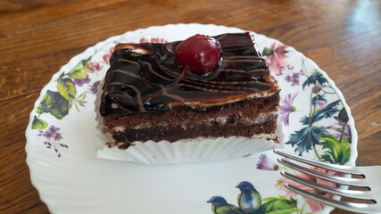 The cherry on top of the cake. Chocolate cake with a cherry on top.