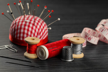 Different sewing tools on wooden table, closeup