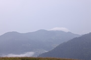 Fototapeta premium Picturesque view of beautiful mountains covered with fog