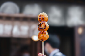 Japanese Mitarashi Dango skewer on woman hand in street food Japan