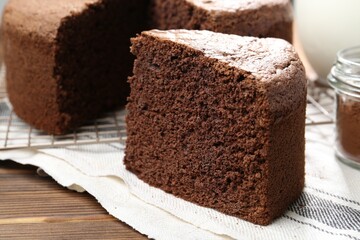 Piece of tasty chocolate sponge cake on wooden table, closeup