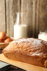 Tasty sponge cake with powdered sugar on table, closeup