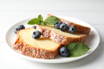 Freshly baked sponge cake, mint and blueberries on white wooden table