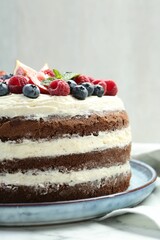 Delicious chocolate sponge cake with berries on white table, closeup