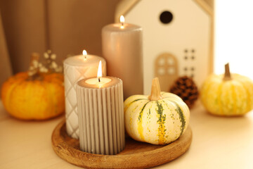 Burning candles and pumpkins on white table, closeup. Autumn atmosphere