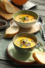 Delicious pumpkin soup served on grey wooden table, closeup