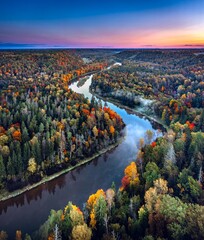 Colorful sunrise over the Gauja National park valley.  Sigulda city panorama from drone with forest...
