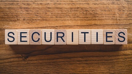 Fototapeta premium Closeup of an aged and weathered wooden board surface with the word SECURITIES carved into the wood representing financial and investment themes empty copy space for text
