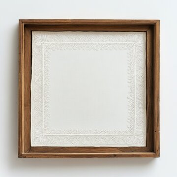 Embroidered white handkerchief in rustic wooden frame displayed on white background
