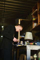 A young man in a garage working with electrical equipment, tinkering with something