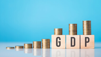 A wooden block labeled 'GDP' next to a stack of coins arranged from smallest to largest. Concept of...