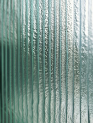 Frosted polycarbonate surface with metallic chrome reflections. Vertical ribbed patterns with abstract textured effect. Cool toned  icy palette. 