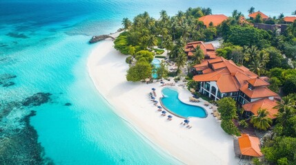 Fototapeta premium An aerial view of a tropical resort. The resort is located on a small island with a white sand beach. There are several buildings on the island, as well as a large pool and many palm trees