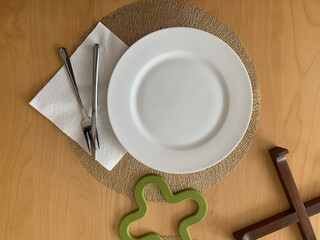 Minimal table setup featuring a clean, white plate with silver fork and knife on a napkin. Perfect for food-related projects, cooking blogs, or restaurant promotions
