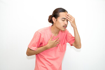 An Indonesian, Asian man wearing a pink tshirt having a headache, chest pain and stomach ache with hands holding head, chest and stomach. isolated in white background