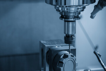 The CNC milling machine cutting the graphite electrode parts in the light blue scene.