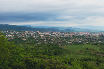 Aerial view of the lush landscape and urban area of Nagorno Karabakh under cloudy skies during the late afternoon