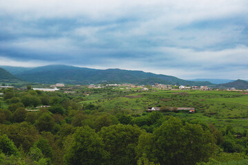 Scenic view of Nagorno Karabakh landscape featuring lush greenery and distant mountains under a cloudy sky