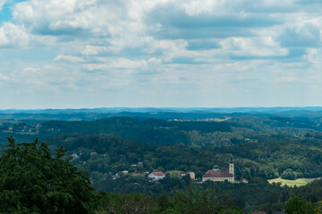 Majestic church Basilika Mariastrost with a two dome surrounded by rolling hills covered in lush green forests near Graz, Styria, Austria, Europe. Dramatic contrast against the dark green of the trees